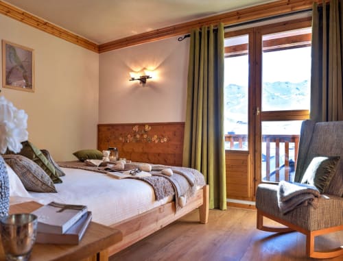 Chambre alpine de luxe avec vue sur les montagnes, lit en bois, cheminée et balcon aux Étoiles de la Plagne