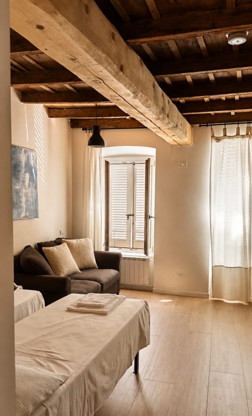 Geräumiges Schlafzimmer in Bergamo mit freigelegten Holzbalken, gemütlichem Sitzbereich und Fensterläden