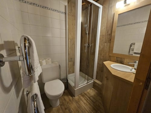 Salle de bain moderne avec toilettes séparées, douche, lavabo, vanité en bois et porte-serviettes chauffant aux Étoiles de la