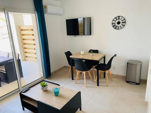 Appartamento moderno a Résidence Marina di Bravone con tavolo da pranzo, sedie nere, TV e accesso al balcone a Linguizzetta
