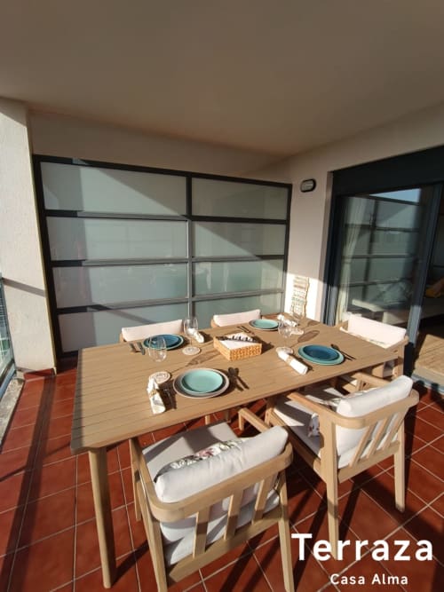 Terrasse de Casa Alma à Sant Jordi avec table en bois, couverts et porte-garage vitrée