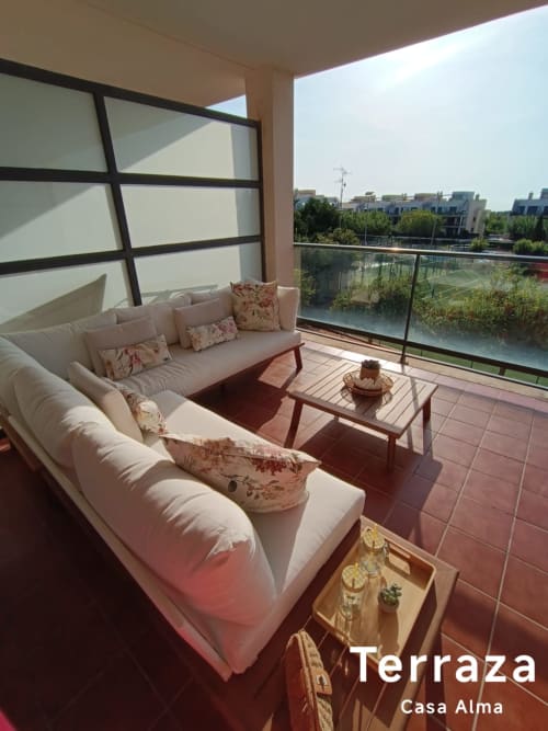 Terrasse ensoleillée de Casa Alma à Sant Jordi avec sièges confortables, table en bois et vue sur l'eau surplombant le quartier résidentiel