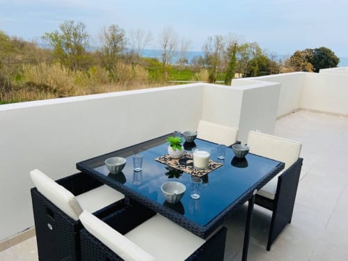 Terrazza moderna sulla Résidence Marina di Bravone con tavolo da pranzo, vista mare e pareti divisorie bianche a Linguizzetta