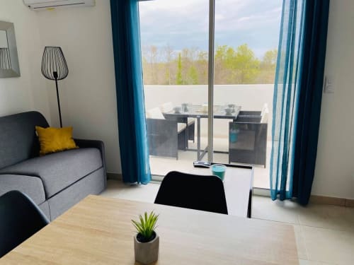 Appartamento moderno a Résidence Marina di Bravone con balcone, vista mare, divano, scrivania e vegetazione primaverile