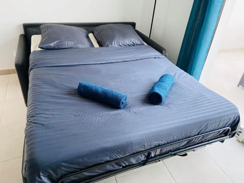 Letto blu con asciugamani arrotolati presso la Résidence Marina di Bravone, Linguizzetta