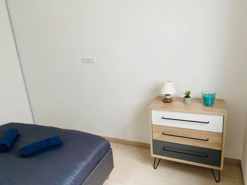 Accogliente camera da letto presso la Résidence Marina di Bravone con letto, comodino in legno, lampada e pianta