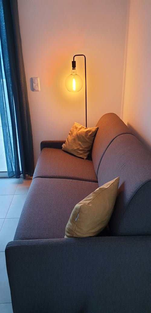 Coin douillet de l'appartement à Marina di Bravone avec suspension chaleureuse, fauteuil gris et coussins dorés