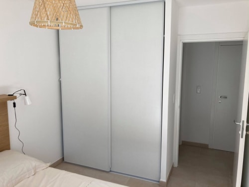 Modern bedroom in Marina di Bravone apartment, Linguizzetta, with built-in wardrobe and woven pendant lamp