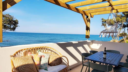 Terrasse en bord de mer à la Résidence Marina di Bravone avec mobilier en rotin, table à manger et vue sur la Méditerranée