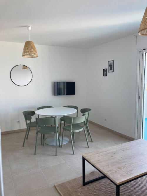 Salle à manger moderne dans appartement T3 à la Résidence Marina di Bravone, Linguizzetta, avec table ronde, chaises vertes et
