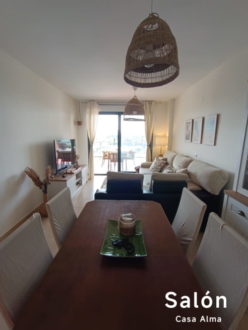 Séjour moderne à l'appartement Casa Alma à Sant Jordi avec table à manger, canapé beige, luminaire suspendu tissé et vue sur le balcon