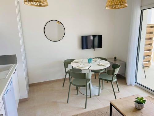 Modern dining area in T2 apartment at Résidence Marina di Bravone, Linguizzetta, with round table, green chairs, and sea view