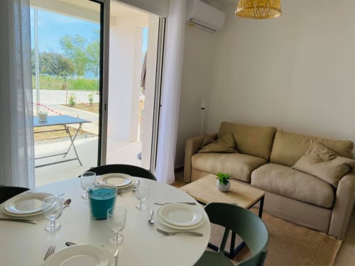 Modern apartment at Marina di Bravone with dining area, beige sofa, and terrace overlooking sandy beach