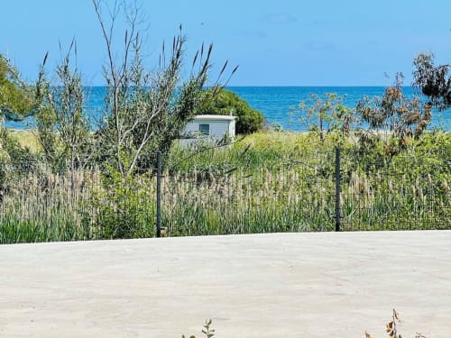 Beachfront apartment view at Résidence Marina di Bravone with sandy beach, blue sea, and coastal vegetation in Linguizzetta