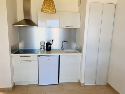 Modern kitchenette at Résidence Marina di Bravone, Linguizzetta, with white cabinets, stainless steel cooktop, and compact
