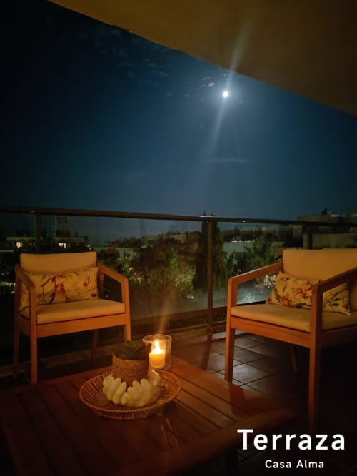 Terrasse Casa Alma de nuit avec deux chaises orange, table à la chandelle et ciel étoilé surplombant Sant Jordi
