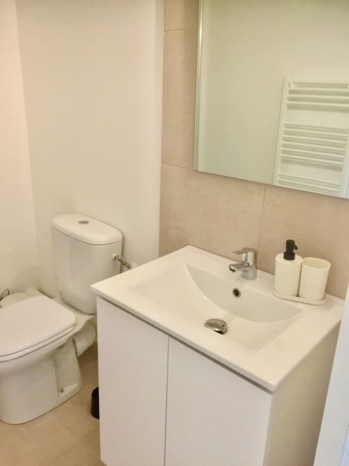 Salle de bain moderne avec vasque blanche, toilettes et carrelage beige à la Résidence Marina di Bravone