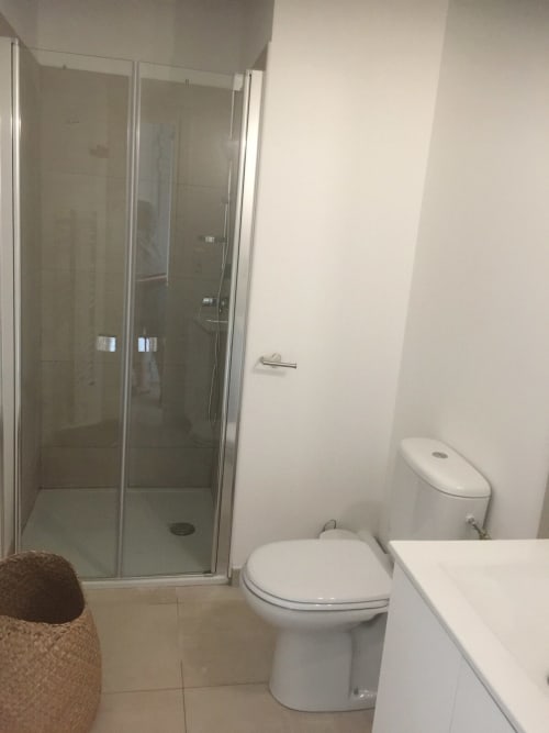 Salle de bains moderne avec douche vitrée, toilettes blanches, lavabo et carrelage beige à la Résidence Marina di Bravone