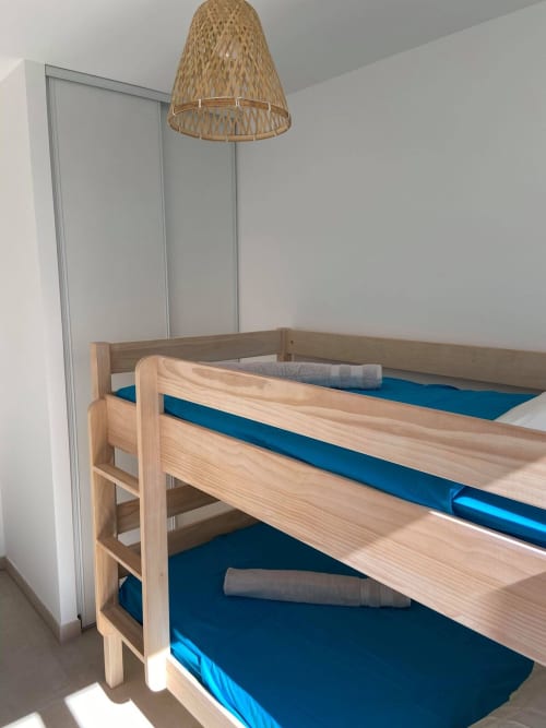 Modern loft-style bedroom at Résidence Marina di Bravone with wooden bunk beds and blue mattresses