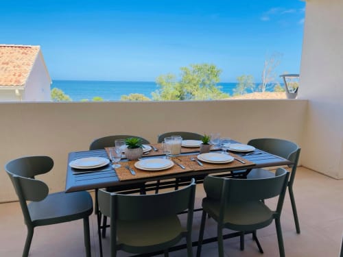 Seaside terrace dining at Marina di Bravone with sea view, set table, black chairs