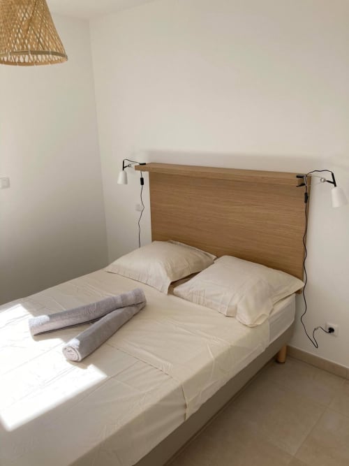 Modern bedroom at Marina di Bravone with wooden headboard, white pillows, rolled towels, and reading lights