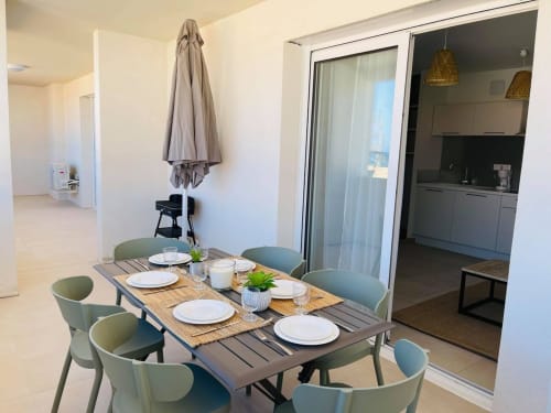 Modern dining area at Résidence Marina di Bravone with set table, sea view patio access, and contemporary kitchen