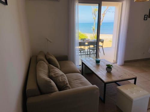 Salon d'appartement en bord de mer à la Résidence Marina di Bravone avec vue océan par les portes vitrées
