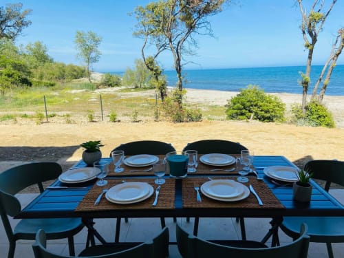Aménagement de table en bord de mer à la Résidence Marina di Bravone avec couverts et vue sur la mer