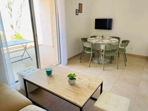 Appartement moderne en bord de mer à la Résidence Marina di Bravone avec table à manger, TV, table basse en bois et balcon vue mer