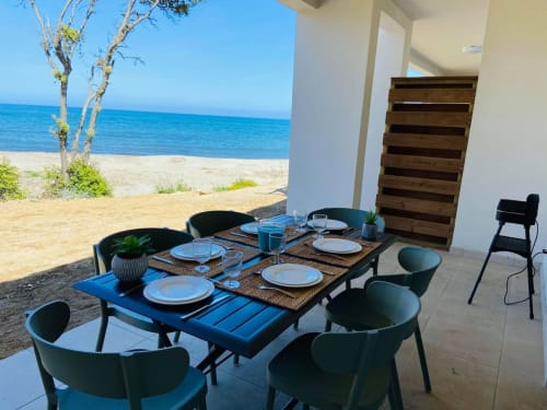 Espace de restauration en bord de mer à la Résidence Marina di Bravone avec table, chaises noires et vue sur l'océan à Linguizzetta