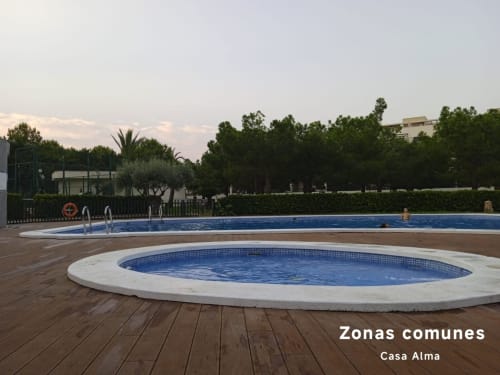 Espace commun à la piscine de Casa Alma à Sant Jordi avec bain à remous circulaire et grand bassin entouré de palmiers