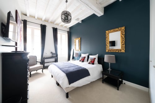 Chambre luxueuse au Pavillon Des Millésimes, Lussac avec mur d'accent bleu canard, miroirs dorés et équipements modernes