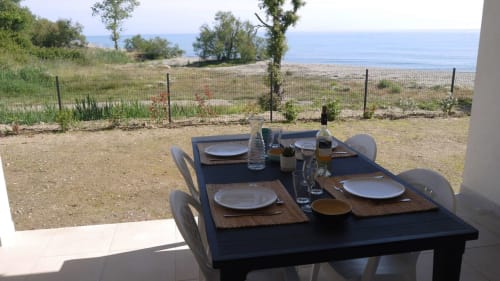 Terrazza fronte mare con tavolo apparecchiato alla Résidence Marina di Bravone, vista su spiaggia e mare