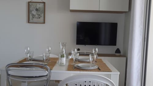 Zona pranzo in appartamento fronte mare presso la Résidence Marina di Bravone, Linguizzetta, con tavolo apparecchiato e TV a parete