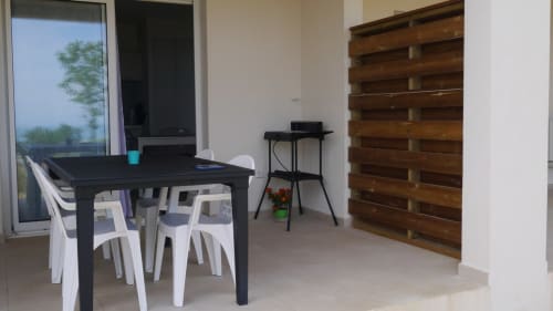 Zona living moderna della Résidence Marina di Bravone con tavolo da pranzo, sedie bianche, arredo in legno e vista mare