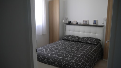 Camera moderna alla Résidence Marina di Bravone con biancheria a motivi geometrici e testata chiara a Linguizzetta