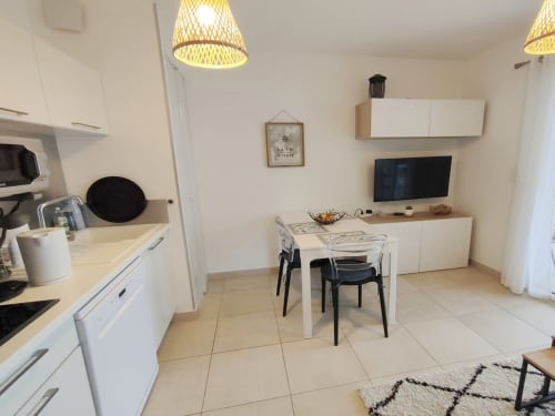 Moderno monolocale a Résidence Marina di Bravone con cucina open-plan, zona pranzo con sedie, TV e arredamento bianco