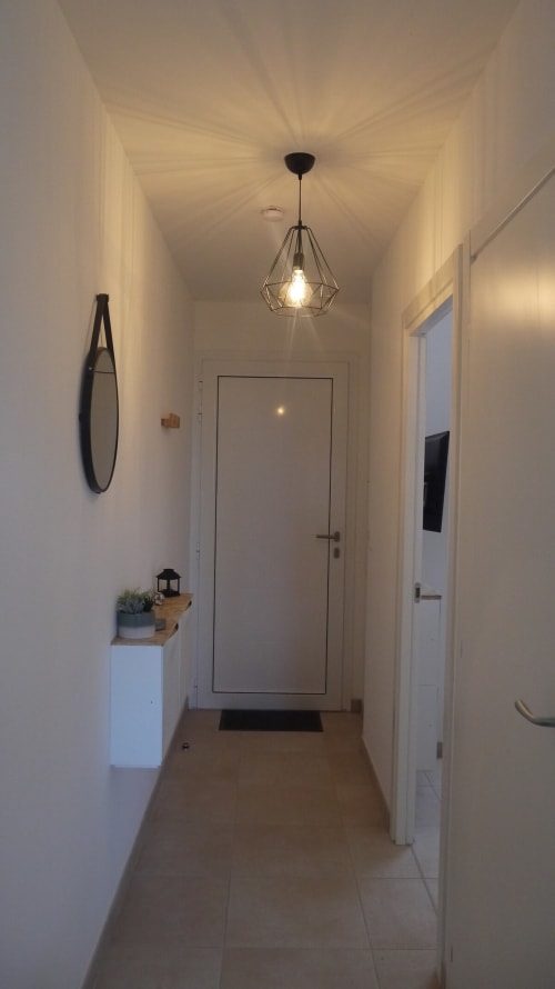Corridoio moderno di Résidence Marina di Bravone con lampada geometrica a sospensione, arredamento minimalista e dettagli in legno