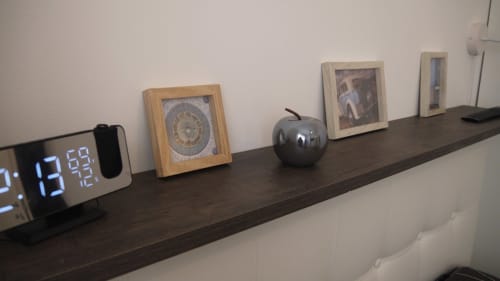 Ripiano in legno scuro con orologio digitale, ruota zodiacale incorniciata, decorazione mela nera e foto incorniciate alla Résidence