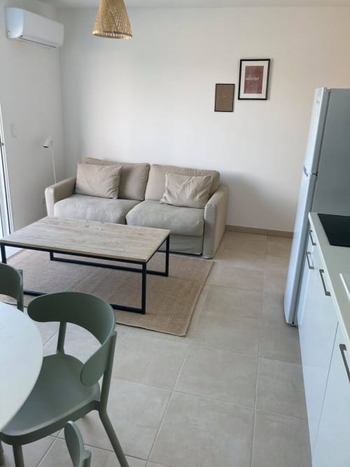Modern apartment living room at Résidence Marina di Bravone with beige sofa, wooden table, and coastal décor in Linguizzetta