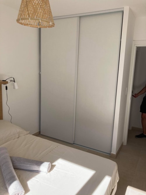 Modern bedroom at Marina di Bravone with white sliding wardrobe, natural lighting, and coastal hotel furnishings