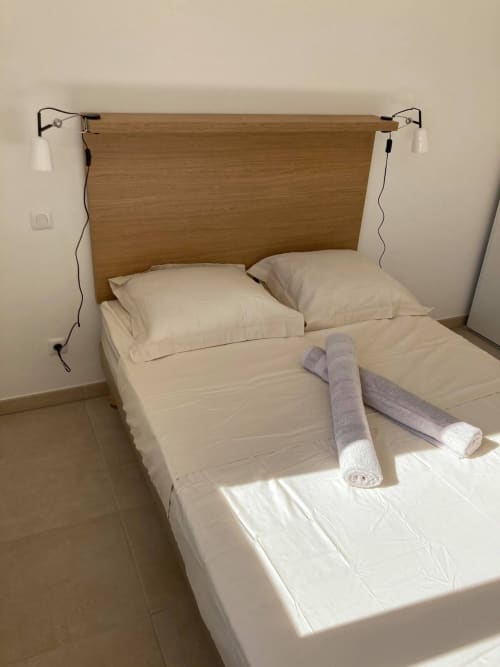 Coastal apartment bedroom at Résidence Marina di Bravone with wooden headboard, white linens, and rolled towels