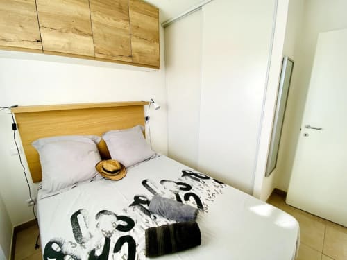 Modern bedroom at Résidence Marina di Bravone hotel in Linguizzetta with wooden bed, white bedding, and pool view from