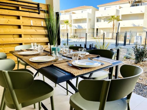Outdoor dining terrace at Résidence Marina di Bravone with set table, green chairs, and pool view in Linguizzetta