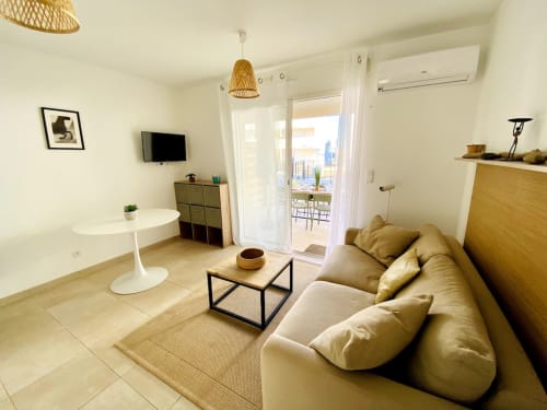 Modern T3 apartment at Résidence Marina di Bravone with beige sofa, dining table, and seafront balcony view