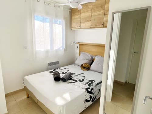 Bright bedroom at Résidence Marina di Bravone with wooden bed frame, white bedding, storage cabinets, and window with sea