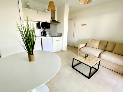 Appartement moderne ouvert à la Résidence Marina di Bravone à Linguizzetta avec canapé beige, cuisine blanche et table ronde