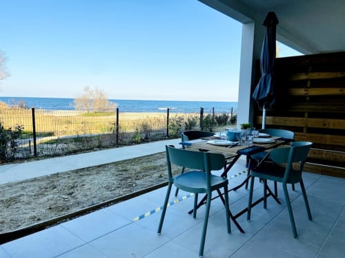 Terrasse vue mer de l'appartement Résidence Marina di Bravone avec table à manger, chaises turquoise et panorama marin à Linguizzetta