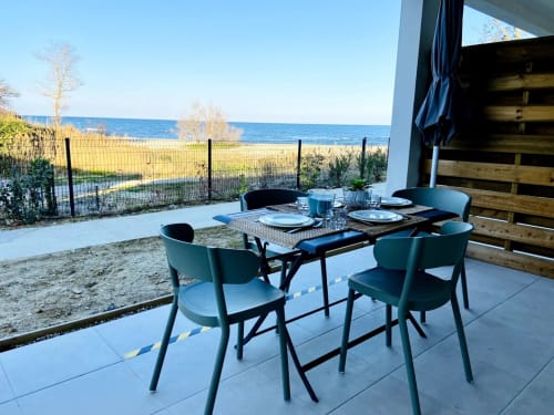 Espace de restauration en bord de mer à la Résidence Marina di Bravone avec table, chaises et vue sur la mer à Linguizzetta