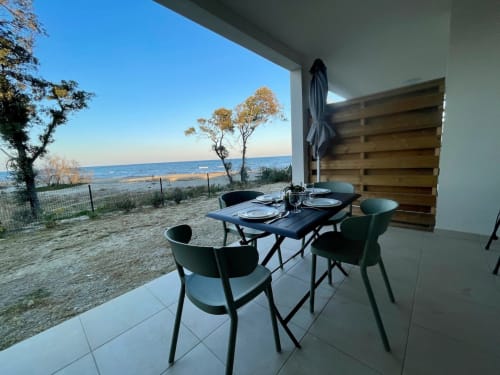 Espace de restauration en bord de mer à l'appartement Marina di Bravone surplombant la plage corse avec table et chaises